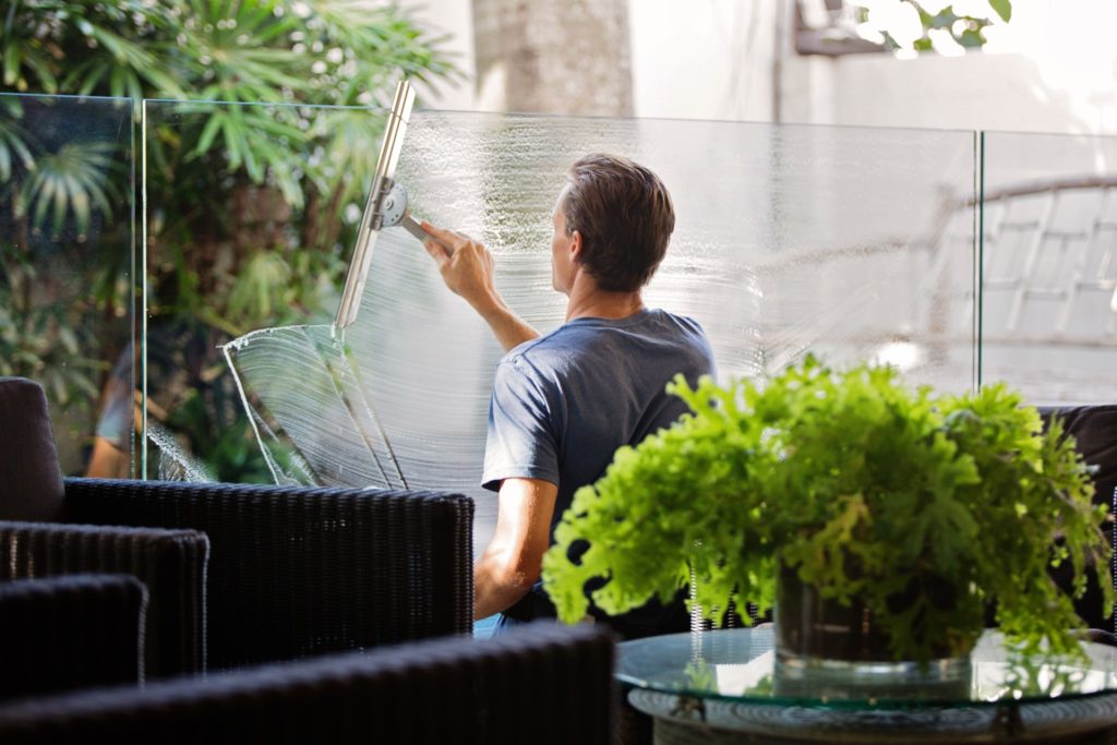 man-in-gray-shirt-cleaning-clear-glass-wall